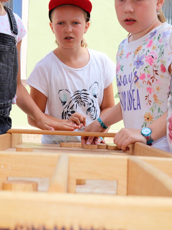 Am 1. Juli begrüßten die SchülerInnen der Volksschule Franz-Fischer-Straße Bürgermeister Georg Willi bei ihrem Sommerfest mit Spielen aus alter Zeit. Nicht nur die Kinder, auch der Bürgermeister waren trotz Hitze mit Feuereifer bei der Sache.