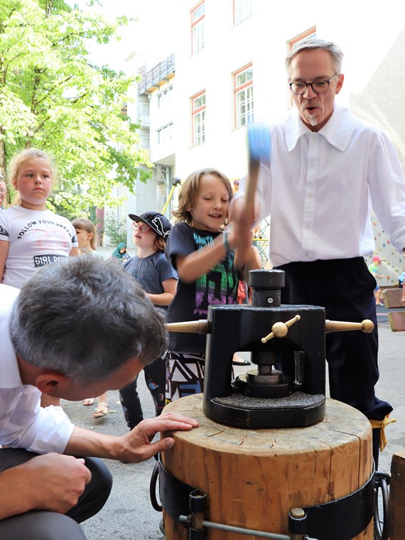 Am 1. Juli begrüßten die SchülerInnen der Volksschule Franz-Fischer-Straße Bürgermeister Georg Willi bei ihrem Sommerfest mit Spielen aus alter Zeit. Nicht nur die Kinder, auch der Bürgermeister waren trotz Hitze mit Feuereifer bei der Sache.