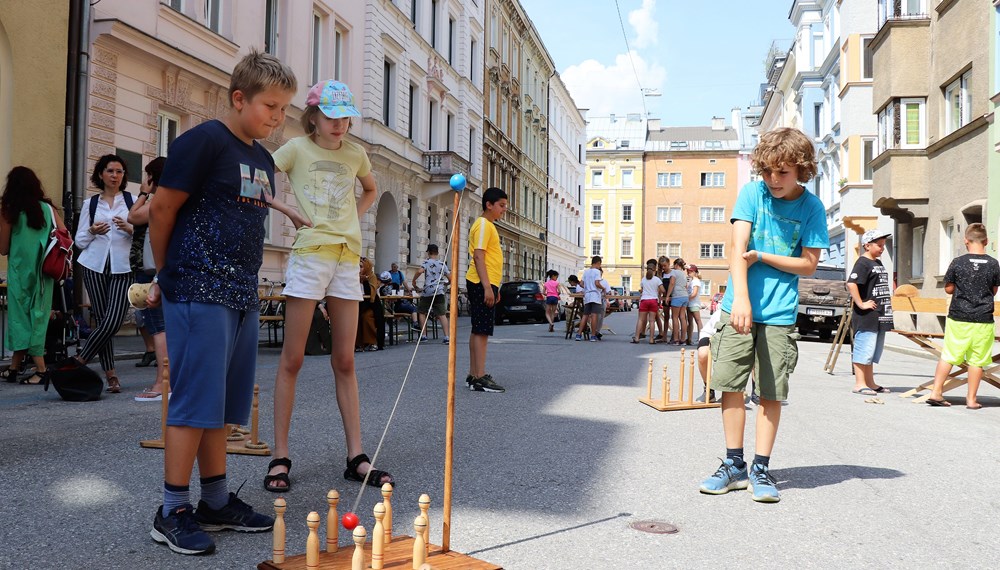 Am 1. Juli begrüßten die SchülerInnen der Volksschule Franz-Fischer-Straße Bürgermeister Georg Willi bei ihrem Sommerfest mit Spielen aus alter Zeit. Nicht nur die Kinder, auch der Bürgermeister waren trotz Hitze mit Feuereifer bei der Sache.