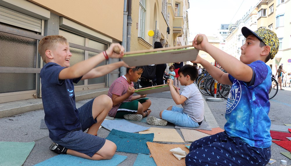 Am 1. Juli begrüßten die SchülerInnen der Volksschule Franz-Fischer-Straße Bürgermeister Georg Willi bei ihrem Sommerfest mit Spielen aus alter Zeit. Nicht nur die Kinder, auch der Bürgermeister waren trotz Hitze mit Feuereifer bei der Sache.