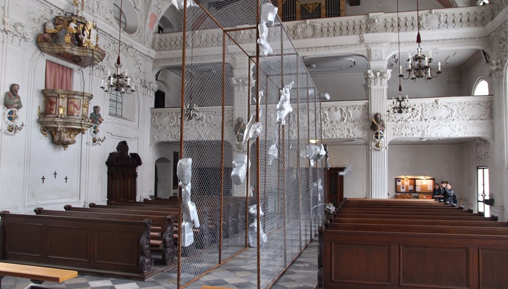 Ein Kunstwerk holt das aktuelle weltpolitische Geschehen nach Innsbruck: Bis Ende September sind vor und in der Innsbrucker Spitalskirche Objekte des Tiroler Künstlers Alois Schild zu sehen. Die Kunstinstallation ist eine Anspielung auf den von US-Präsident Donald Trump in Auftrag gegebenen Mauerbau an der Grenze zu Mexiko und macht einerseits die Abschottungspolitik gegenüber Menschen auf der Flucht und die Radikalisierung der Gesellschaft zum Thema, hält zugleich aber die Hoffnung auf die Überwindung von Spaltung und Ausgrenzung aufrecht.
Auf den Mauerbau, der in den Köpfen vieler Menschen auch in Europa vor sich gehe, weist Bürgermeister Georg Willi hin. „Wir übersehen dabei, wie sehr dieser neue Mauerbau an den Grundsätzen der Demokratie, an der Europäischen Friedensordnung und an den Menschenrechten rüttelt“, so Willi: „Diese Mauern trennen, sie spalten uns aber auch im Inneren und wir verlernen, Brücken zu bauen und aufeinander zuzugehen.“ Neben der Kunst sei es immer wieder auch die Kirche, die daran erinnere, „Brücken und nicht Mauern zu bauen“, so der Bürgermeister. Mehr Informationen zur Ausstellung unter www.dibk.at/Meldungen/Von-der-Mauer-zum-Korridor