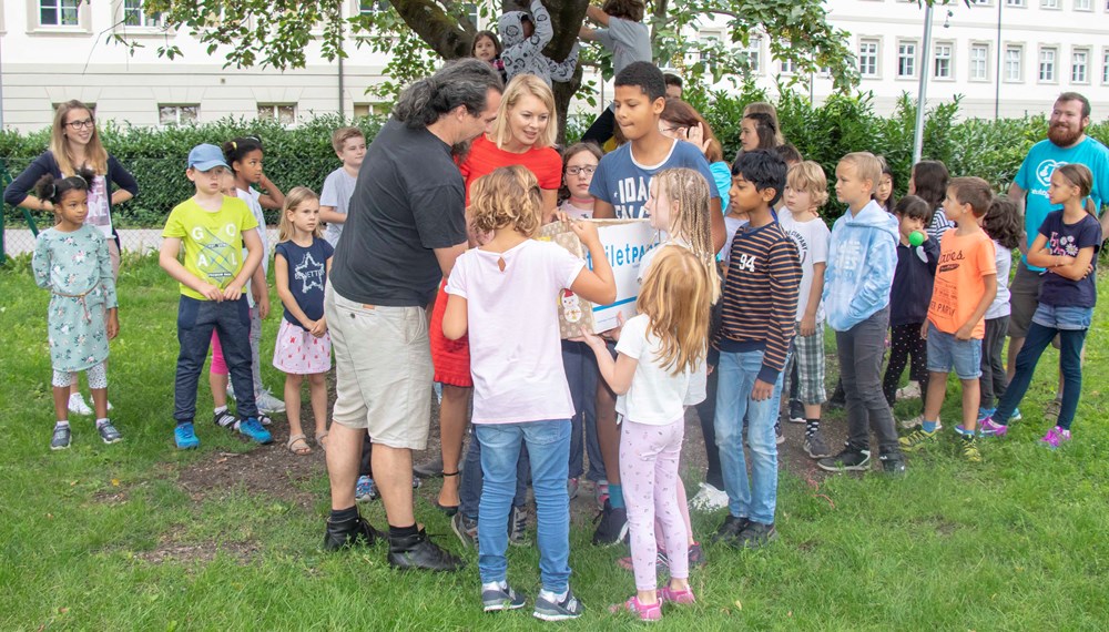 Anlässlich des Endes der Ferienbetreuung im Tagesheim der Kinderfreunde Tirol in der Volkschule Innere Stadt besuchte Stadträtin Mag.a Elisabeth Mayr (Mitte) das Tagesheim und bedankte sich bei den PädagogInnen der Kinderfreunde Tirol für die gelungene Sommerbetreuung. Dem Geschäftsführer des Vereins für Obdachlose, Michael Hennermann (l.), wurde in diesem Rahmen ein Kiste mit Weihnachtsgeschenken für Notleidende übergeben, welche die Kinder während ihrer Zeit im Tagesheim gesammelt haben. Vor allem lang haltbare Lebensmittel sind in der Kiste enthalten, die an die Obdachlosen weitergegeben werden. Neugierig untersuchen Stadträtin Mayr und Geschäftsführer Hennermann gemeinsam mit den Kindern den Inhalt der Kiste und bedankten sich bei Allen für ihr soziales Engagement.