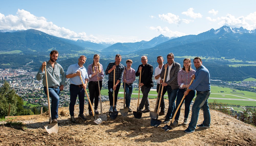 Die Bezirksgruppe der Jungbauernschaft Innsbruck lud zum Spatenstich der geplanten Herz-Jesu-Kapelle am Rauschbrunnen. Neben Bischof Hermann Glettler, zeigten auch Bürgermeister Georg Willi und Vizebürgermeister Franz X. Gruber ihre Unterstützung für das Projekt. Architekt DI Walter Klasz erklärte das auch aus Sicht der Architektur anspruchsvolle Bauvorhaben. Ein Projekt, das nur dank der aktiven Mitarbeit der Jungbauern und -bäurinnen verwirklicht werden wird. Ein Projekt in dem auch viel Herzblut steckt, soll die Kapelle doch einmal auch an die Verstorbenen der Bezirksjungbauernschaft erinnern, als ein Ort des gemeinsamen Gedenkens, des sich Besinnens und des Zusammenseins.