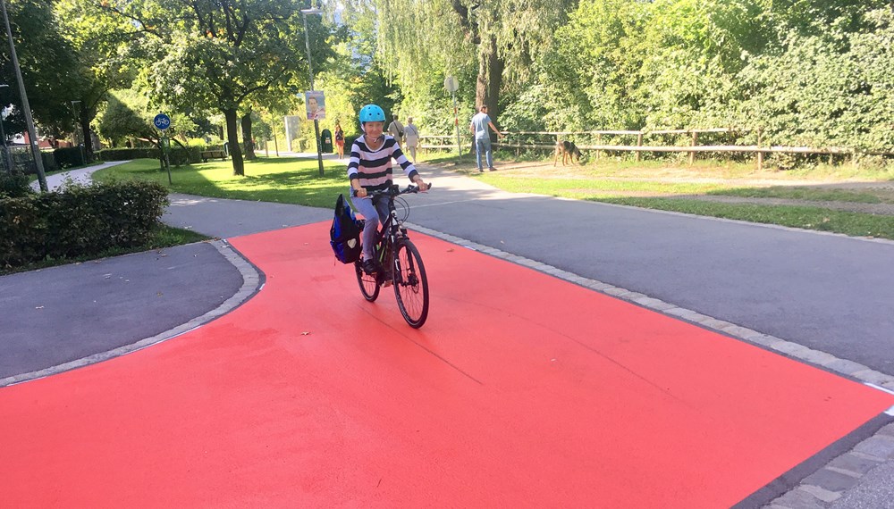 Mobilitätsstadträtin Uschi Schwarzl fährt auf dem roten Teppich Probe, der zu erhöhter Vorsicht zwischen den VerkehrsteilnehmerInnen sorgen soll.