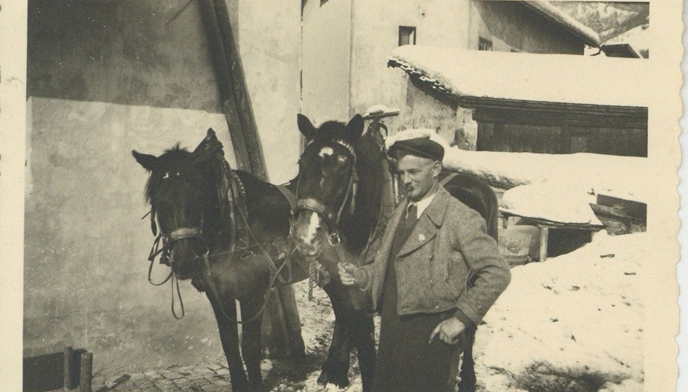 Ein Mann mit zwei Pferden steht vor dem Haus Dorfgasse 9 in Hötting, zwischen 1920 und 1930.