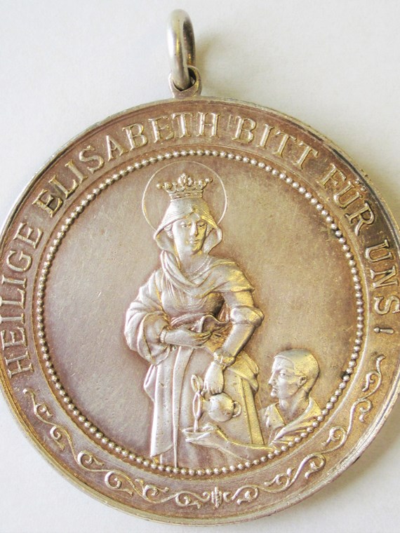 Die hl. Elisabeth von Thüringen gibt einem Durstigen zu trinken. – Medaille der Marianischen Kongregation Bürgerlicher Frauen, Rückseite