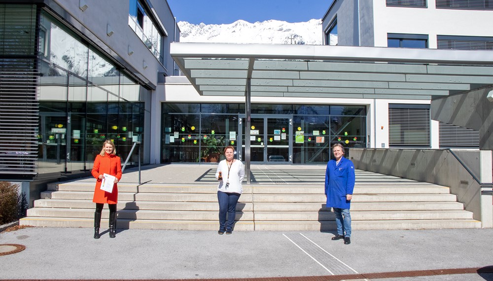 Stadträtin Elisabeth Mayr, Direktorin Ursula Masetti und Schulwart Dietmar Carli mit dem neuen CO2-Messgerät vor der Volksschule Reichenau.