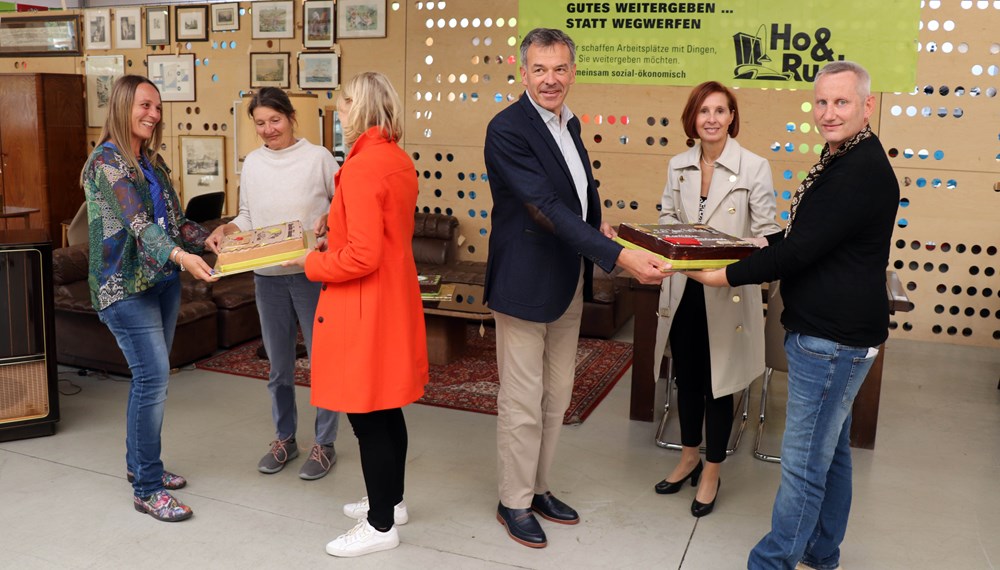 Seit genau 20 Jahren ist das gemeinnützige Unternehmen Ho&Ruck in der ehemaligen Lodenfabrik an der Hallerstraße beheimatet und hat sich zu einer Institution in Innsbruck entwickelt. Bürgermeister Georg Willi (3. v. r.) gratulierte gemeinsam mit den beiden Stadträtinnen Elisabeth Mayr (3. v. l.) und Uschi Schwarzl (2. v. l.) sowie Landesrätin Gabriele Fischer (2. v. r.) anlässlich des runden Jubiläums. Als kleine Aufmerksamkeit überreichten sie zwei prachtvolle Torten an die beiden GeschäftsführerInnen Martina Wolf-Kuntner und Thomas Holzer.