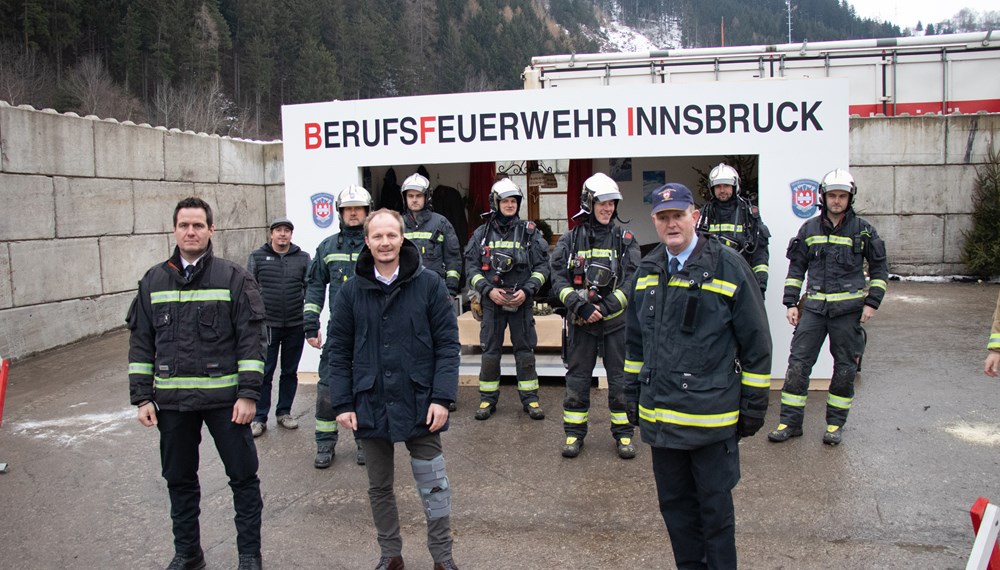 Branddirektor Helmut Hager (links), Vizebürgermeister Johannes Anzengruber, Branddirektor-Stv. Johann Zimmermann und die Löschgruppe der Berufsfeuerwehr vor dem Übungsszenario, das die Folgen eines Christbaumbrandes vor Augen führt.