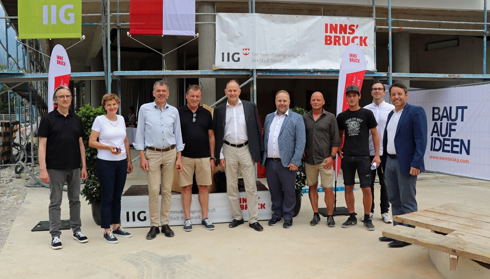 Architekt Andreas Scharmer, Stadträtin Christine Oppitz-Plörer, Bürgermeister Georg Willi, Gemeinderat Helmut Buchacher, IIG-Aufsichtsratsvorsitzender Franz Pegger, Gemeinderat Lucas Krackl, Vertreter der ausführenden Baufirma Swietelsky, Architekt Gabriel Stotter (hinten) und IIG-GF Franz Danler (v.l.n.r.) freuten sich über die gelungene Firstfeier der Wohnanlage in der Amraser Straße 26.