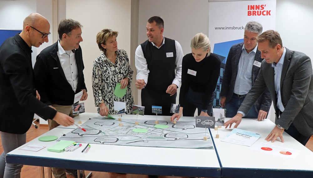 Wolfgang Andexlinger (Stadtplanung, Stadtentwicklung und Integration), Gerhard Hofer (Immobilien, Wirtschaft und Tourismus), Stadträtin Christine Oppitz-Plörer, Philipp Resl (Businesspark Innsbruck), Daniela Allmeier (Raumposition), Markus Dax (GF STEKA Werke, Wirtschaftskammer-Bezirksausschuss Innsbruck-Stadt und Sprecher der Rossau) und Franz Jirka (Bezirksstellenobmann WK Tirol; v.l.n.r.) an einem der vier Themen-Planungstische.