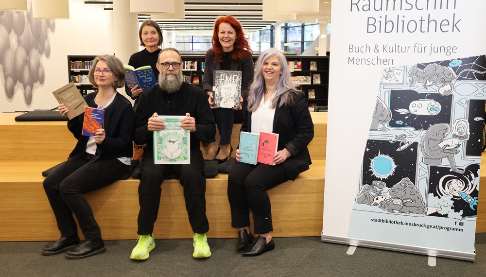 Vitali Konstantinov stellt als einer der AutorInnen bei "Raumschiff Bibliothek" seine Comic-Sachbücher vor: Mit (v.l.) Veronika Knapp (Projektleiterin), Stadträtin Uschi Schwarzl, Landesrätin Cornelia Hagele und Bibliotheksleiterin Christina Krenmayr.