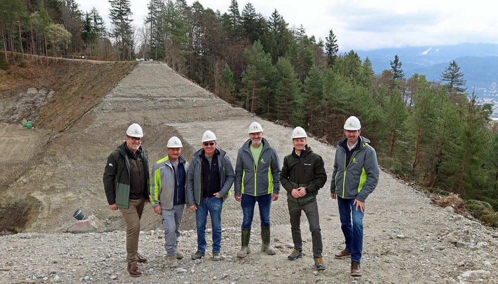 Vizebürgermeister Johannes Anzengruber (2.v.r.), Amtsleiter Andreas Wildauer (Wald und Natur, l.) und Sektionsleiter Gebhard Walter (Wildbach- und Lawinenverbauung, r.) begrüßen gemeinsam mit Mitarbeitern der WLV die Sanierung des Lawinenauffangdamms.