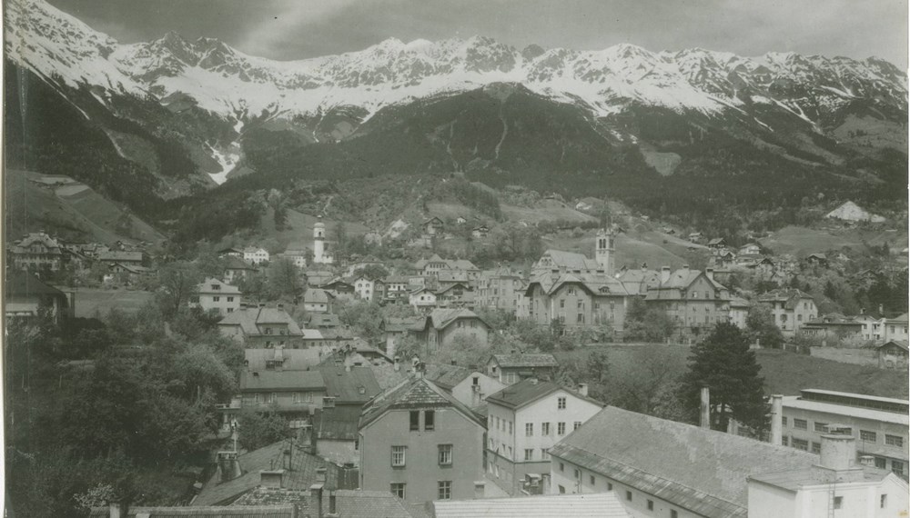 Blick auf das Kirschental im Stadtteil Mariahilf. Im Hintergrund die neue (rechts) und die alte (links) Höttinger Pfarrkirche, aufgenommen von Richard Müller um 1930.