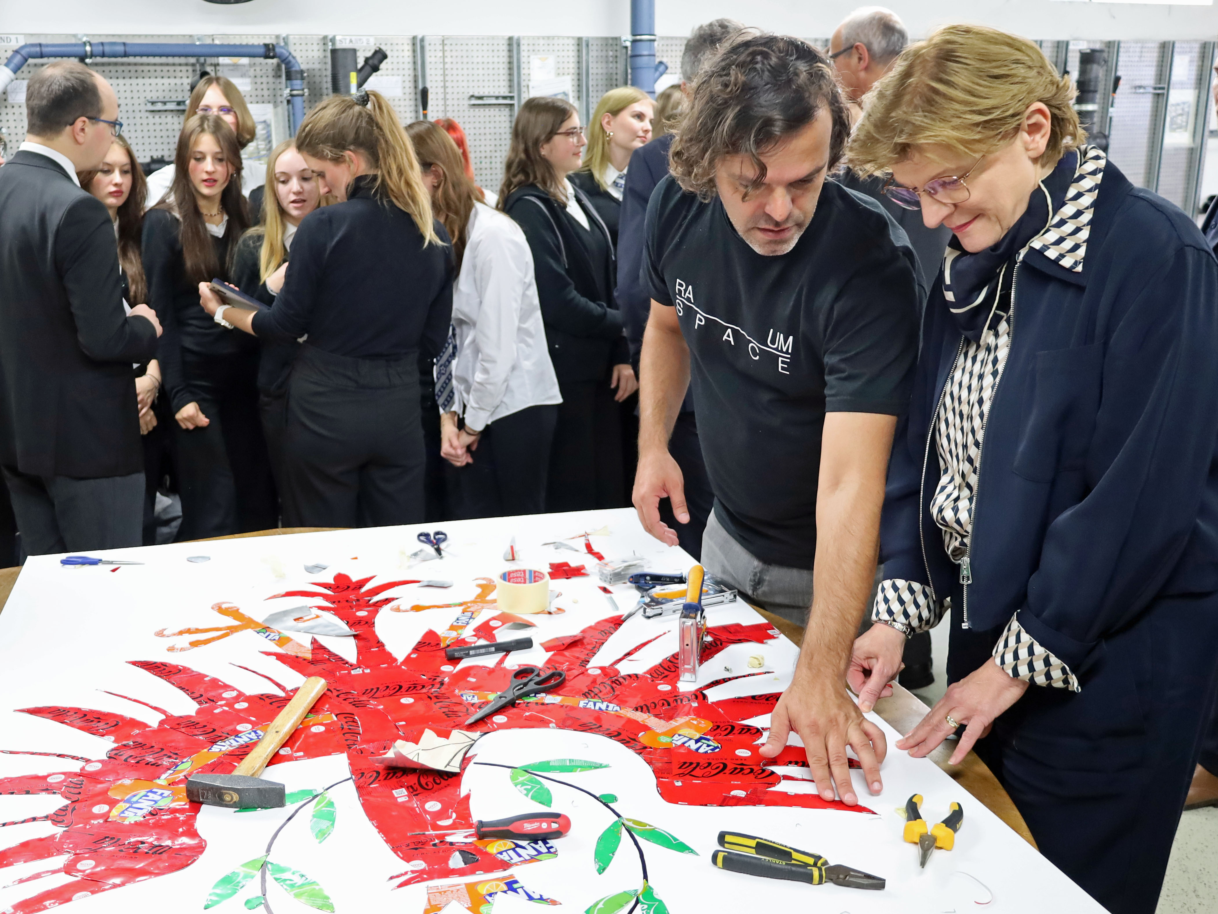 Aus alten Getränkedosen wird der Tiroler Adler: Preisträger José Rodrigues (2.v.r.) und Stadträtin Christine Oppitz-Plörer (r.) bei der Begutachtung des Upcycling-Kunstwerks.
