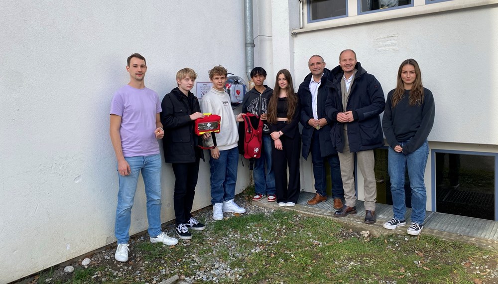 Vizebürgermeister Johannes Anzengruber (2.v.r.), Schuldirektor Walter Nigg (3.v.r.) und Lehrer bzw. Ausbildner Christoph Moser (l.) mit dem SchülerInnen-Emergency-Team und dem neuen Erste-Hilfe- vor dem Defibrillator am Reithmanngymnasium.