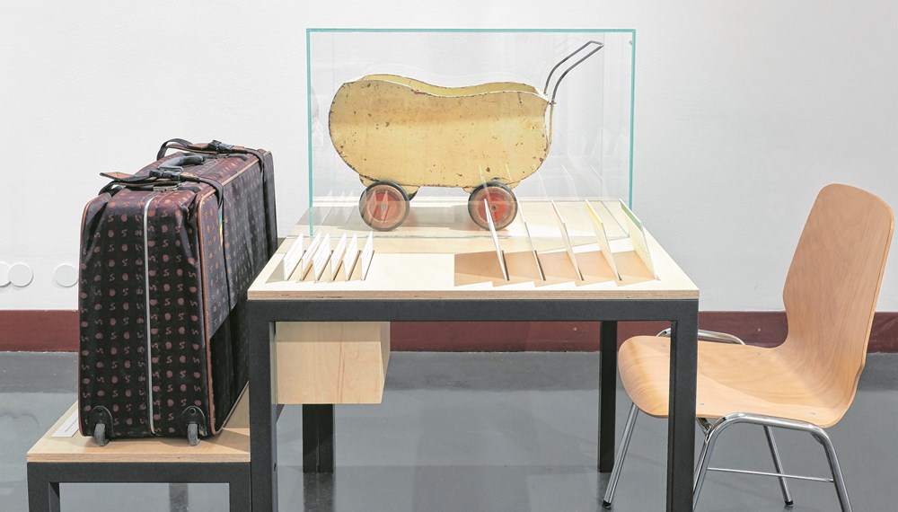 Puppenwagen, aus einer Wehrmachtskiste mit Raubgut aus Frankreich getischlert. Daneben der Koffer, in dem dieses Objekt dem hdgö von der Besitzer-Familie übergeben wurde.