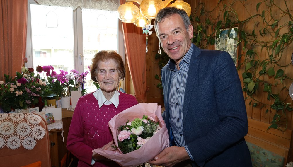Bürgermeister Georg Willi (r.) überreicht Maria Weger einen Blumenstrauß zum 100. Geburtstag.