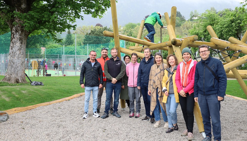 Große Freude anlässlich der Eröffnung des Ursulinenparks: Stadträtin Uschi Schwarzl (4. v.r.), Amtsvorstand Thomas Klingler (Mitte) mit seinem Team vom Referat Grünanlagen – Planung und Bau und Patricia Klahn (ISD-Stadtteilkoordinatorin Höttinger Au, 2. v.r.). Im Hintergrund der multifunktionale Ballspielplatz, der – wie auch das neue Klettergerüst – bereits eifrig ausprobiert wurde.