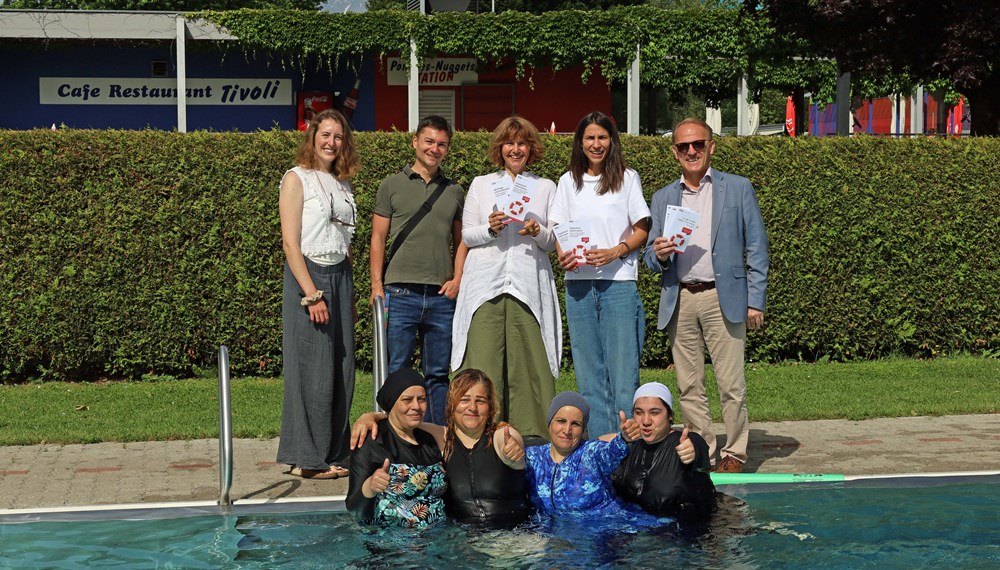 Schwimmen lernen im Freibad Tivoli: Vier der Teilnehmenden mit Christina Köhle (Schwimmschule „Schwimmwerk“), Florian Stolz (TSD), Nicola Köfler (Strategie und Integration), Integrationsstadträtin Janine Bex und Geschäftsbereichsleiter Mag. Ulrich Mayerhofer (IKB).