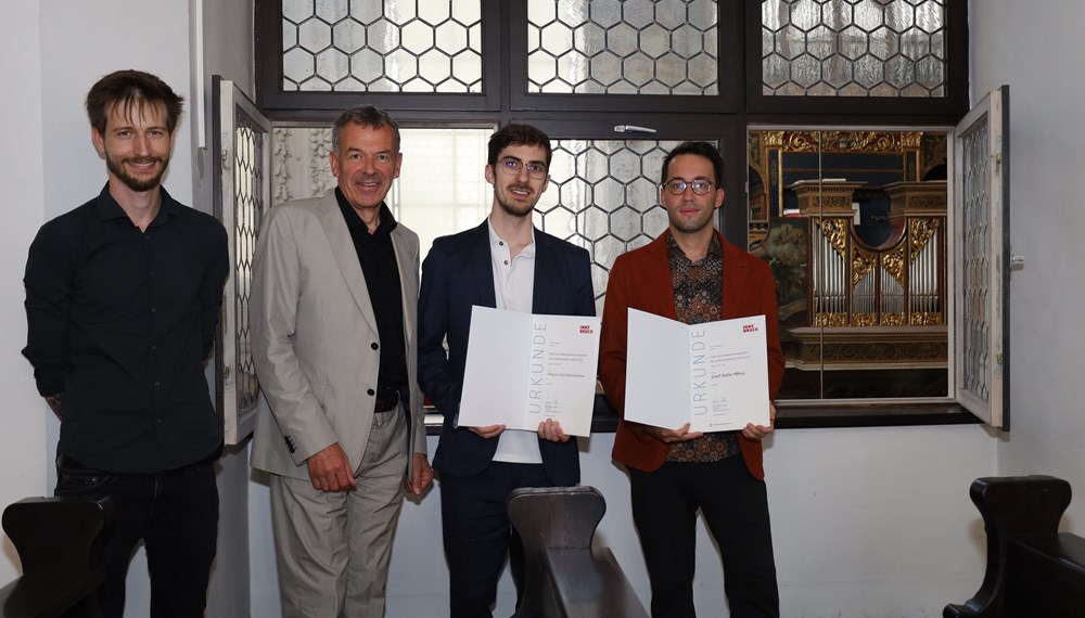 Die Preisträger Josef Haller (1. v.r.) und Gabriel Bramböck (2. v.r.) vor der Ebertorgel, der ältesten Orgel Österreichs (1558), in der Innsbrucker Hofkirche. Vizebürgermeister Georg Willi und Markus Margreiter (Kulturamt, 1. v.l.) gratulierten herzlich zum Hilde-Zach-Kompositionsstipendium 2024.