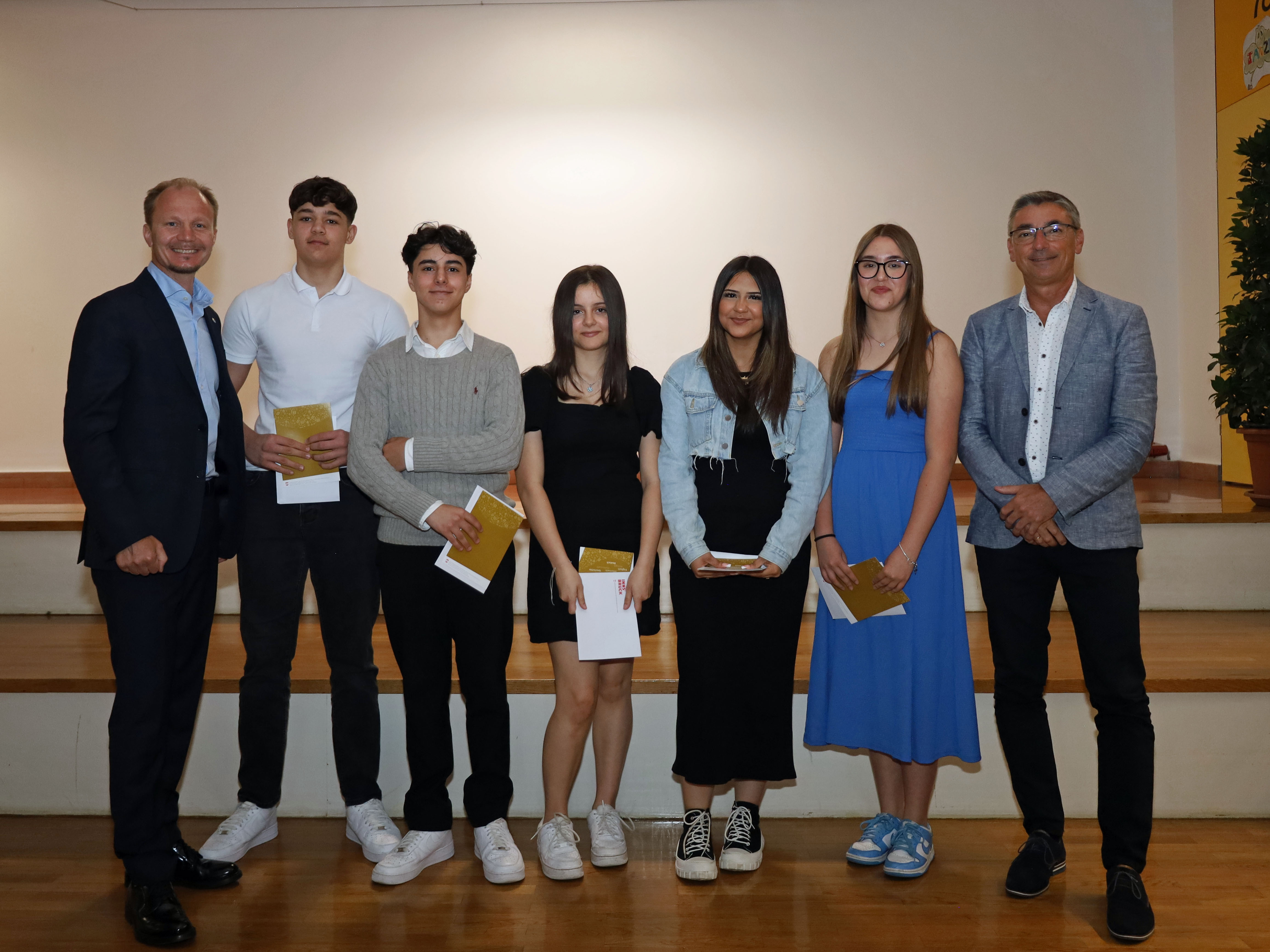 Bürgermeister Johannes Anzengruber (l.) und Schulqualitätsmanager Dietmar Meinschad (r.) mit den ausgezeichneten SchülerInnen der Mittelschule Leopoldstraße.