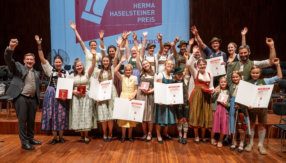 Seit 50 Jahren findet der Alpenländischen Volksmusikwettbewerb in Innsbruck statt. Vergangenes Wochenende war es wieder soweit. MusikantInnen aus dem gesamten Alpenraum brachten Innsbruck zum Klingen. Vom 24. bis 27. Oktober war Innsbruck wieder die Hauptstadt der Alpen in Sachen Volksmusik.
Alle zwei Jahre treffen sich mehr als 700 junge MusikantInnen und SängerInnen aus vier Ländern – Österreich, Bayern, Südtirol und der Schweiz – um beim wichtigsten internationalen Musikwettbewerb für alpenländische Volksmusik in Europa, dem 25. Alpenländischen Volksmusikwettbewerb (Herma Haselsteiner-Preis), ihr Können zu präsentieren. Beim abschließenden Festabend überreichte Hans Peter Haselsteiner die begehrten Herma-Haselsteiner-Preise.
Diese gingen heuer an die Familienmusik Eßl aus Salzburg, die Geschwister Strasser und die Saitenstraßen Musi aus Bayern, an die Gesangsgruppe Glanschlzwüllinge aus Kärnten, die Gesangssolistin Daria Occhini aus der Schweiz und an die Hackbrettmusig der Landesmusikschule Kitzbühel. Untertags musizierten hunderte VolksmusikantInnen in der Innsbrucker Altstadt und im Congress.
Der Obmann des Tiroler Volksmusikvereins Peter Margreiter freute sich über den enormen Besucherandrang: „Dass dieses einzigartige Volksmusikfest auch nach 50 Jahren so eine riesige Anziehungskraft ausstrahlt, macht uns als Veranstalter sehr stolz und wir freuen uns die lebendige Kulturlandschaft Innsbrucks mit erlesener Volksmusik bereichern zu dürfen.“ Nach Ende des offiziellen Festabends wurde natürlich noch lange in die Nacht hinein gefeiert und musiziert. Unter den Gästen waren unter anderem Unterstützer und Kulturmäzen Hans Peter Haselsteiner mit seiner Frau Ulli, Landeshauptmann Anton Mattle, LH-Stellv. Josef Geisler, der Bürgermeister der Stadt Innsbruck, Johannes Anzengruber sowie Bischofsvikar Probst Jakob Bürgler.