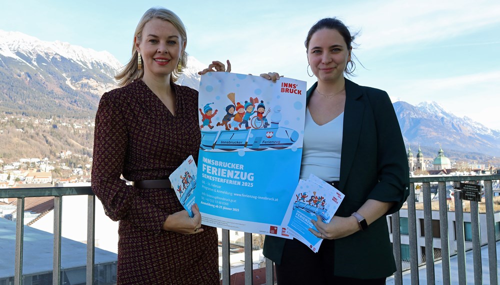 Vizebürgermeisterin Elisabeth Mayr und Eva Pichler (re.) präsentieren den Ferienzug-Fahrplan für Feber 2025.