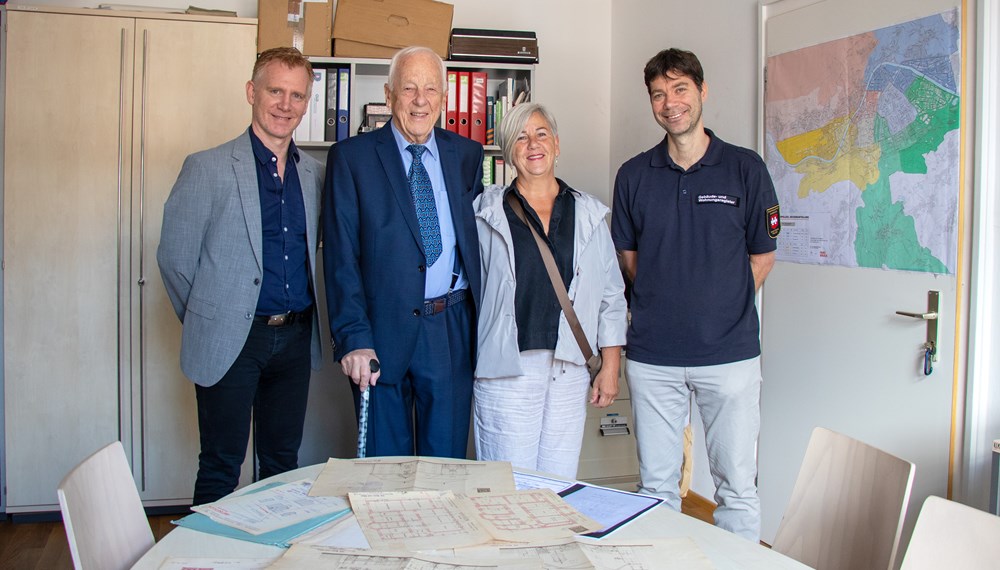 Ein Stück Innsbrucker Baugeschichte wurde heute im Amt Bau- und Feuerpolizei lebendig: Dem 94-jährigen Norbert Benzer wurden gemeinsam mit seiner Tochter Andrea Duplikate der historischen Bestandspläne seines Wohnhauses aus dem Jahr 1902 überreicht – gefertigt von der bis heute bestehenden Firma Huter & Söhne. Der rüstige Innsbrucker, der 1931 genau in jenem Haus in der Elisabethstraße geboren wurde, in dem er noch immer lebt, plant zum Abschluss seines Lebens eine Umbaumaßnahme im Gebäude: „Ich möchte meine Flügel noch ein wenig ausstrecken“, so Benzer mit einem Schmunzeln.
Gemeinsam mit Amtsvorstand Christian Kugler und Referent Manfred Hirsch vom Gebäude- und Wohnungsregister wurden die historischen Unterlagen eingehend studiert. Dabei hatte Herr Benzer so manche Anekdote aus fast einem Jahrhundert Hausgeschichte zu erzählen – von berühmten Untermietern bis hin zu einer einst verschwundenen Küche. Vielleicht wird man diese Geschichten bald in einem geplanten Podcast hören können, der Innsbrucker ZeitzeugInnen und ihre Erinnerungen zu Wort kommen lässt.