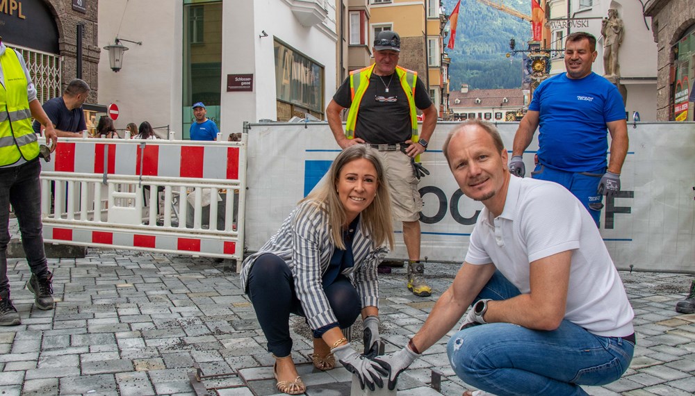 Bürgermeister Johannes Anzengruber und Stadträtin Mariella Lutz setzen gemeinsam den letzten Pflasterstein in der Herzog-Friedrich-Straße und besiegeln damit den Abschluss der Arbeiten in der Innsbrucker Altstadt.