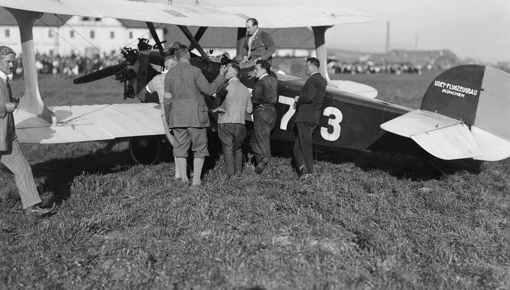 Ernst Udet (auf der Maschine sitzend) und fünf Männer
mit dem Doppeldecker Udet U 12 „Flamingo“ auf dem
Flughafen Reichenau.