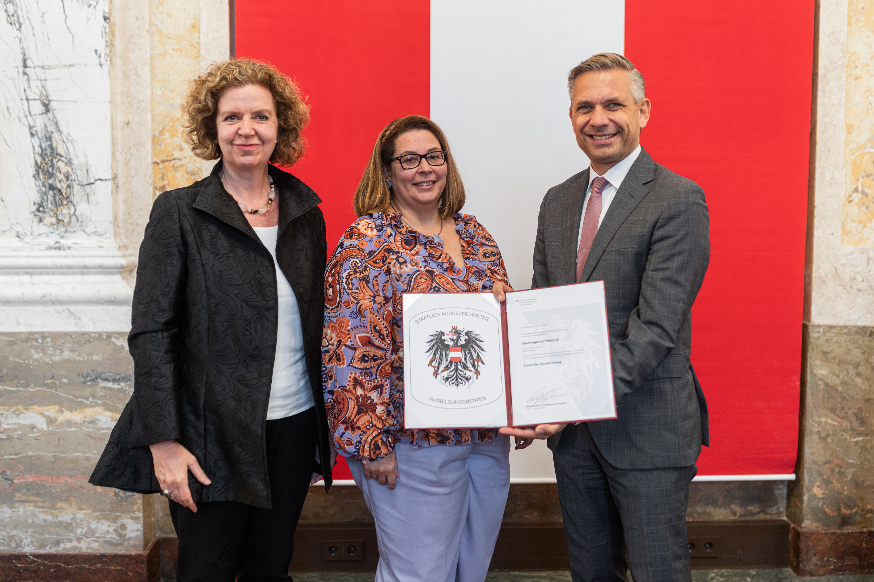(v. l.) Magistratsdirektorin Gabriele Herlitschka und Lehrlingsbeauftragte Sabine Floßmann nehmen im Namen der Stadt Innsbruck das Gütesiegel „Staatlich ausgezeichneter Ausbildungsbetrieb“ von Bundesminister Wolfgang Hattmannsdorfer entgegen.
