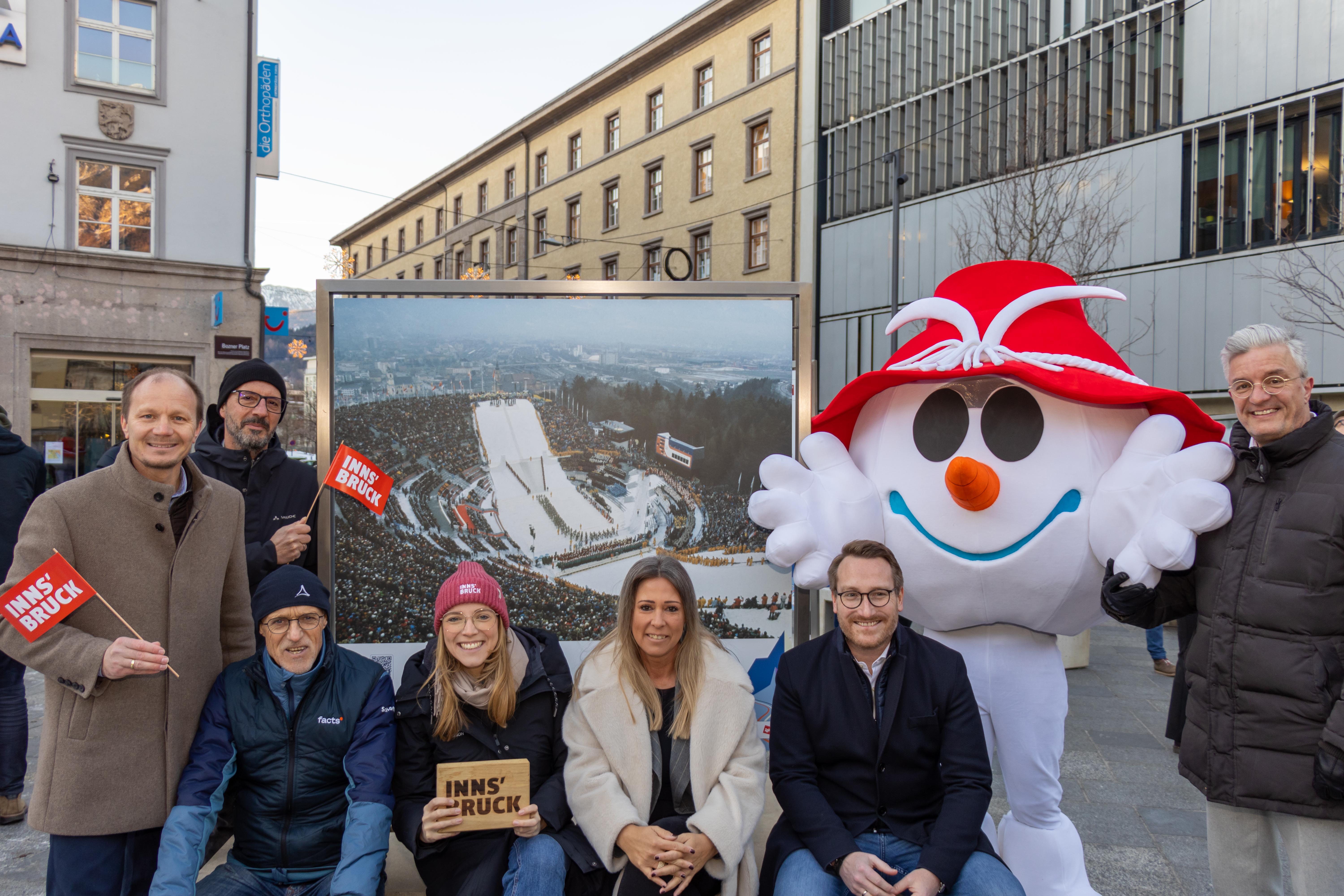 Die Eröffnung der Olympia-Fotoausstellung (v.l.n.r.): Bürgermeister Johannes Anzengruber, Peter Paul Mölk (Obmann Innsbruck Tourismus), Toni Innauer (Silber Skispringen 1976), Barbara Plattner (Geschäftsführung Innsbruck Tourismus), Stadträtin Mariella Lutz, Landeshauptmann-Stellvertreter Philip Wohlgemuth, Vereinsobmann Michael Perger (Zentrumsverein) sowie Olympia-Maskottchen Snowy.