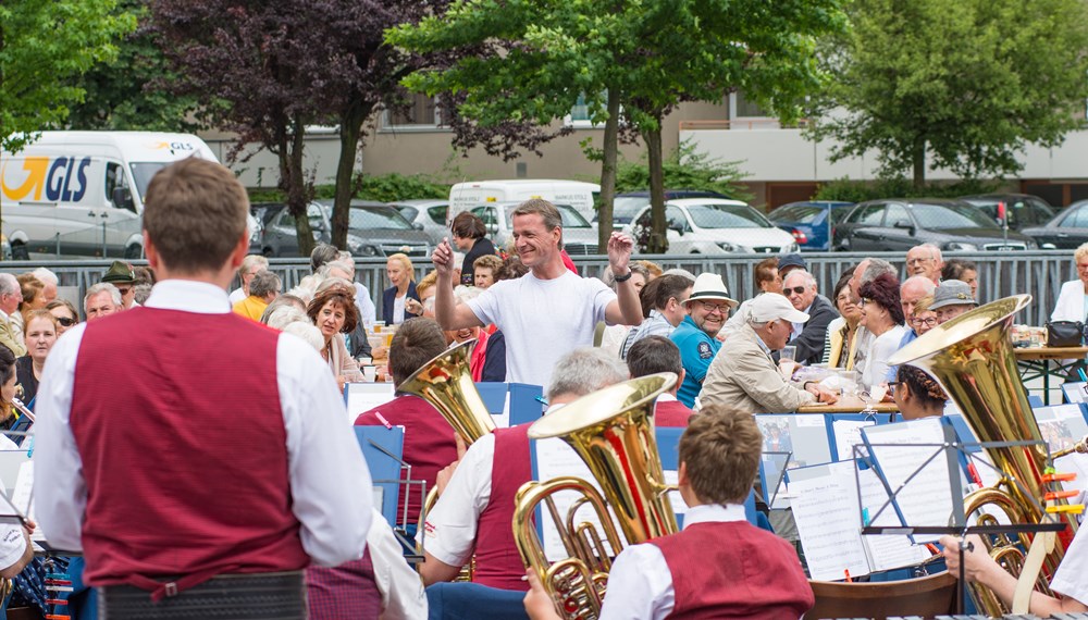 Vizebürgermeister Christoph Kaufmann eröffnete das Platzkonzert der Speckbacher Musikkapelle am DDr. Alois Lugger Platz. Gemeinsam mit der Pfarre St. Pius X und der Freiwilligen Feuerwehr Neu Arzl organisierte die Speckbacher Musikkapelle einen Frühschoppen im Olympischen Dorf .