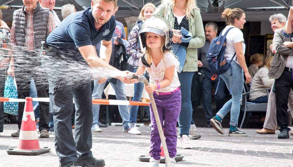 Einmal im Jahr findet in der Landeshauptstadt das „Peterle hilft“-Sicherheitsfest statt. Bei der diesjährigen Auflage Mitte September erfuhren die Kinder im Rahmen einer Quizrallye viel Lehrreiches und Unterhaltsames zum Thema Sicherheit im Herbst. Im Stadtturm galt es, auf Peterles Spuren zu wandern und unter anderem eine geheime Grotte zu entdecken. In der Herzog-Friedrich-Straße gaben Peterles Freunde von Polizei, Berufsfeuerwehr, Rotem Kreuz, Mobile Überwachungsgruppe (MÜG) und Bergrettung kindgerecht wichtige Sicherheitstipps – selbst ausprobieren stand ebenfalls am Programm. Vizebürgermeisterin Christine Oppitz-Plörer (2.v.l.) stattete den Vertretern der Einsatzorganisationen und Organisatorin Uschi Klee (Referat Frauen und Generationen, 2.v.r.) einen Besuch beim Fest ab.